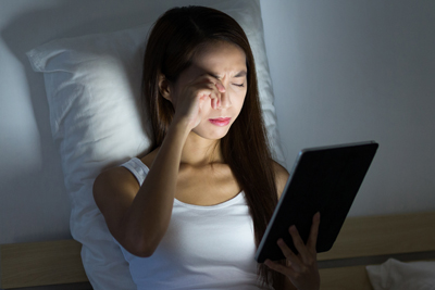 Woman feeling eye pain when using tablet at night