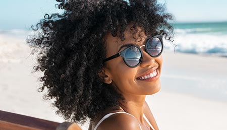 Woman wearing sunglasses by a beach
